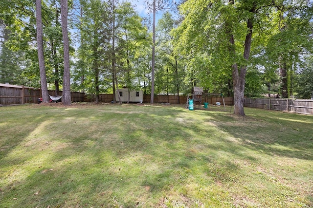 view of yard with an outdoor structure, a fenced backyard, a playground, and a storage shed