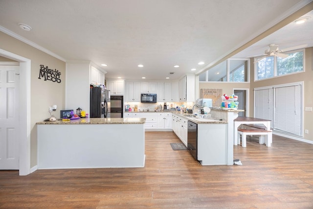 kitchen featuring ornamental molding, a peninsula, white cabinetry, a sink, and black appliances