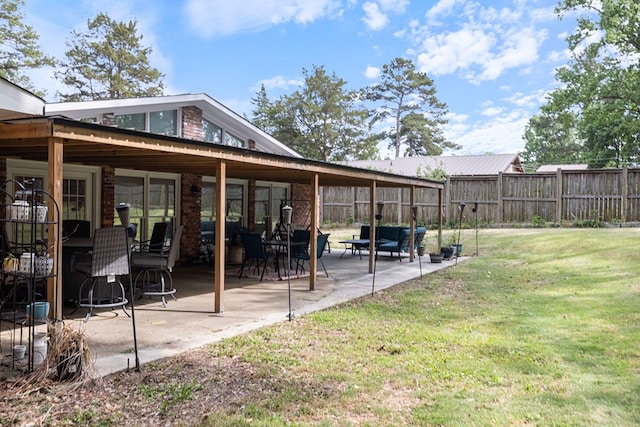 rear view of house with a lawn, a patio area, fence, and brick siding
