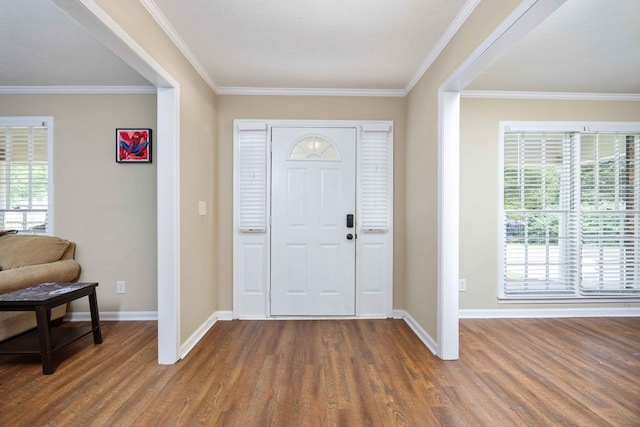 foyer entrance with baseboards, crown molding, and wood finished floors