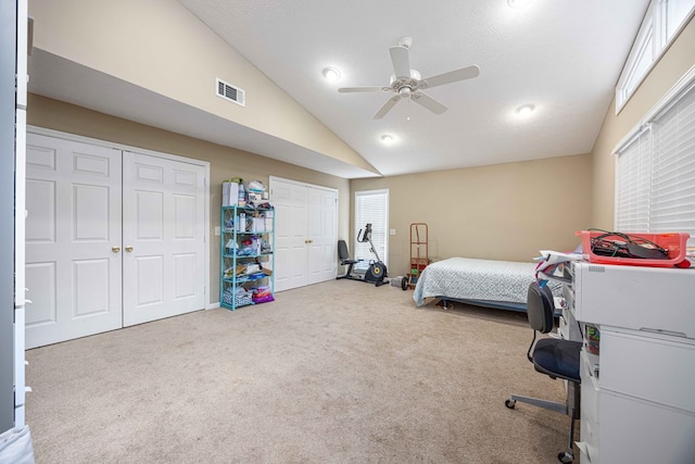bedroom featuring visible vents, multiple closets, lofted ceiling, a ceiling fan, and carpet