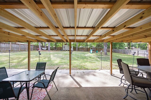 view of patio / terrace with outdoor dining area, a fenced backyard, a shed, a playground, and an outbuilding