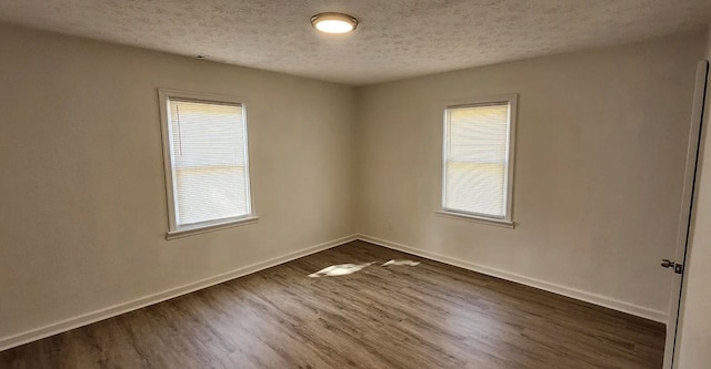 unfurnished room featuring baseboards, dark wood-style flooring, a wealth of natural light, and a textured ceiling