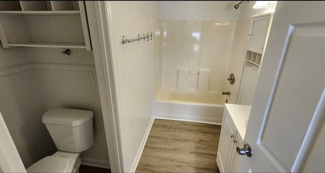 full bath with shower / tub combination, toilet, vanity, and wood finished floors