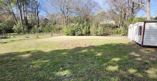 view of yard featuring an outbuilding, a storage shed, and fence