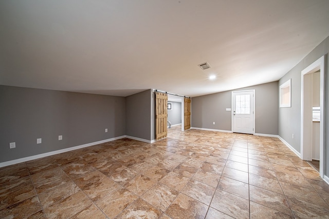 interior space with visible vents, baseboards, and a barn door