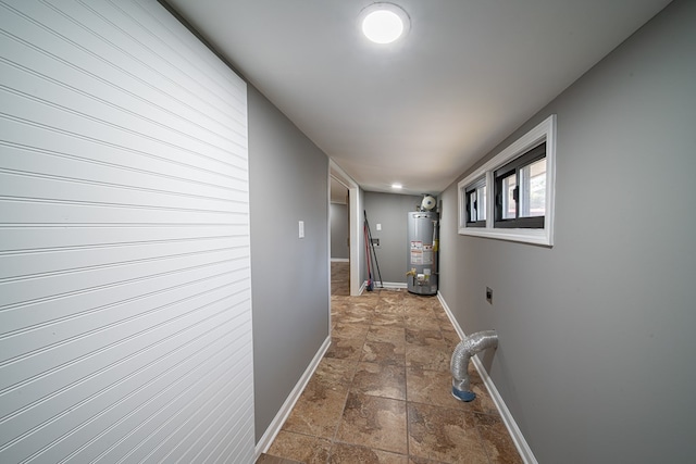 hall with baseboards, water heater, and stone finish floor