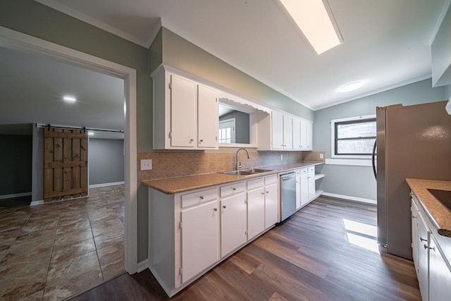 kitchen featuring dishwasher, a barn door, decorative backsplash, white cabinetry, and a sink