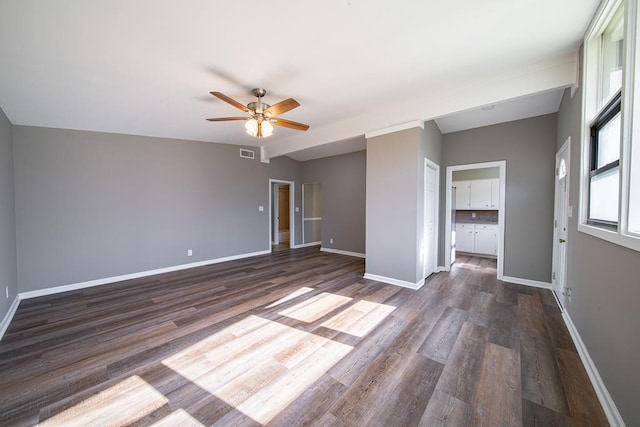 empty room featuring visible vents, ceiling fan, dark wood-type flooring, and baseboards