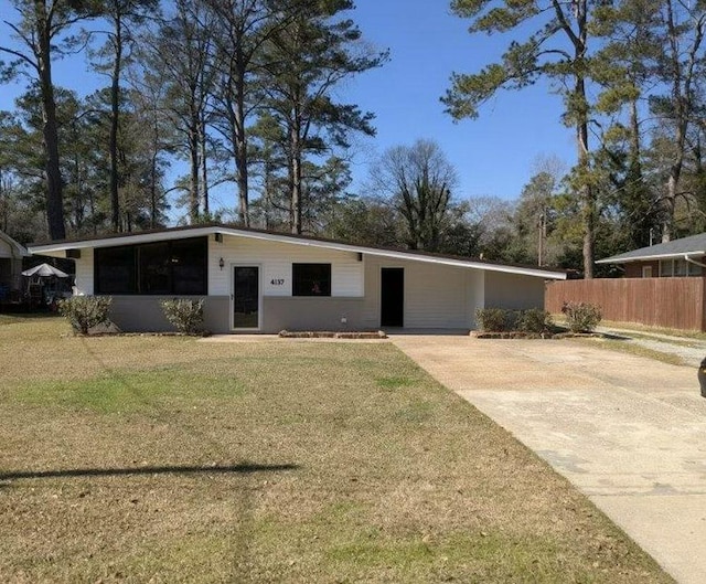 mid-century home featuring a carport, driveway, a front yard, and fence