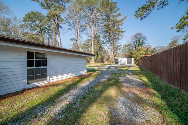 view of yard featuring an outbuilding, fence, and driveway