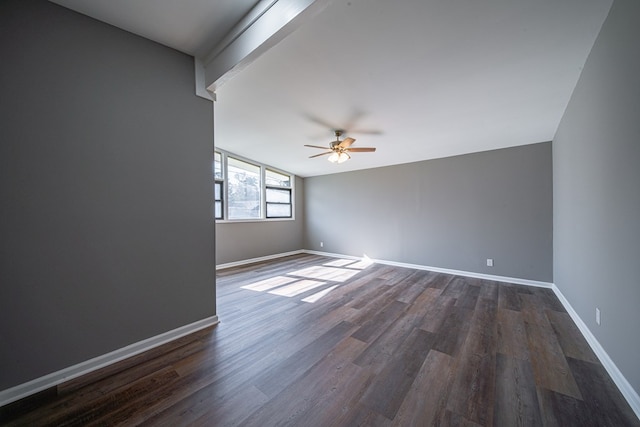 empty room featuring dark wood-style floors, a ceiling fan, lofted ceiling with beams, and baseboards