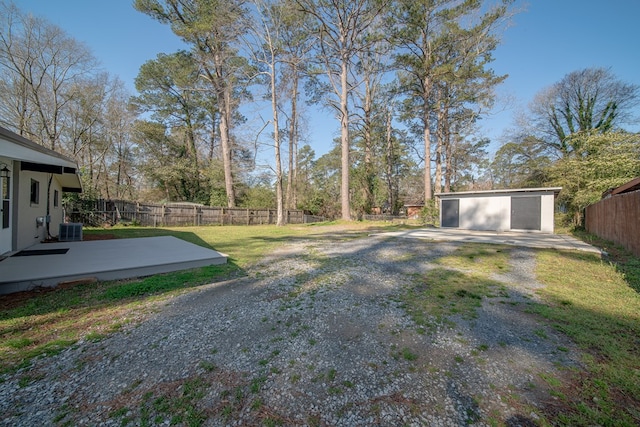 view of yard with an outbuilding, central air condition unit, fence, and a patio