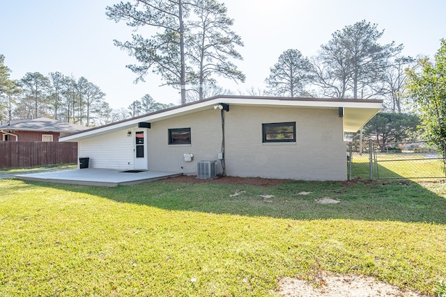 rear view of property with brick siding, fence, central AC unit, a yard, and a patio area