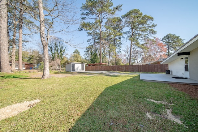 view of yard with an outbuilding, a shed, a patio area, and fence