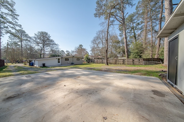 view of home's exterior with a patio, a lawn, concrete driveway, and fence