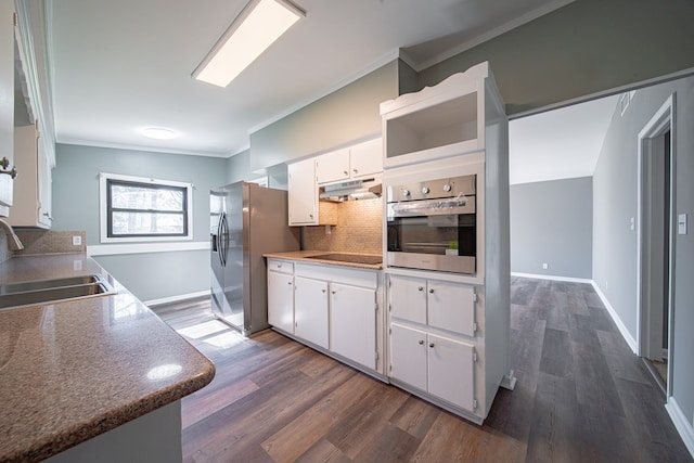 kitchen featuring a sink, under cabinet range hood, backsplash, appliances with stainless steel finishes, and crown molding