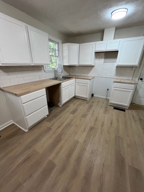 3015 Walker St, Columbus, GA 31903 - kitchen featuring decorative backsplash, white cabinets, light wood-type flooring, and a textured ceiling