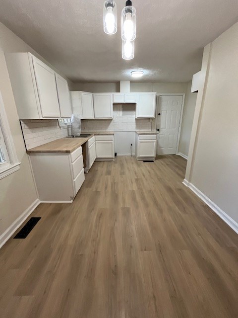 3015 Walker St, Columbus, GA 31903 - kitchen with white cabinetry, decorative backsplash, wood finished floors, and decorative light fixtures