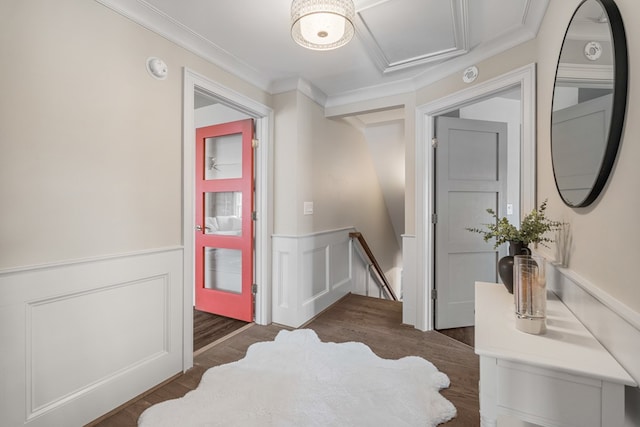 corridor with wood finished floors, a wainscoted wall, ornamental molding, a decorative wall, and an upstairs landing