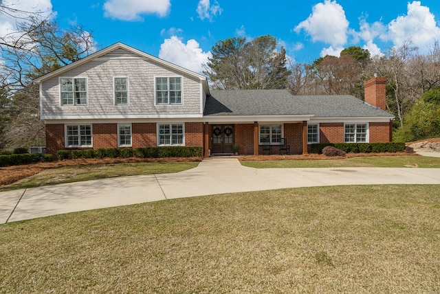 view of front of property featuring a front lawn, brick siding, and a chimney