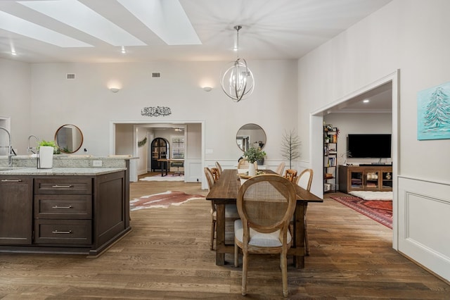 dining room featuring visible vents, a wainscoted wall, a skylight, dark wood-type flooring, and a chandelier