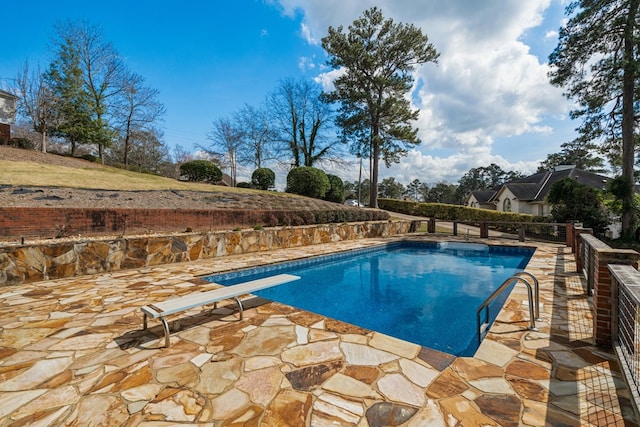 view of pool with a patio, a fenced in pool, and a diving board