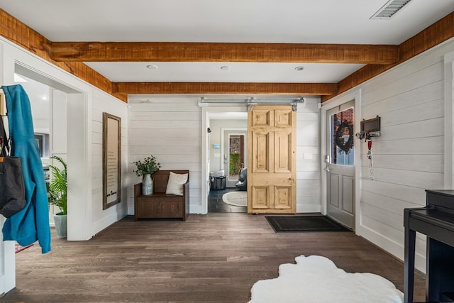 foyer entrance featuring visible vents, beam ceiling, wood walls, and dark wood-style flooring