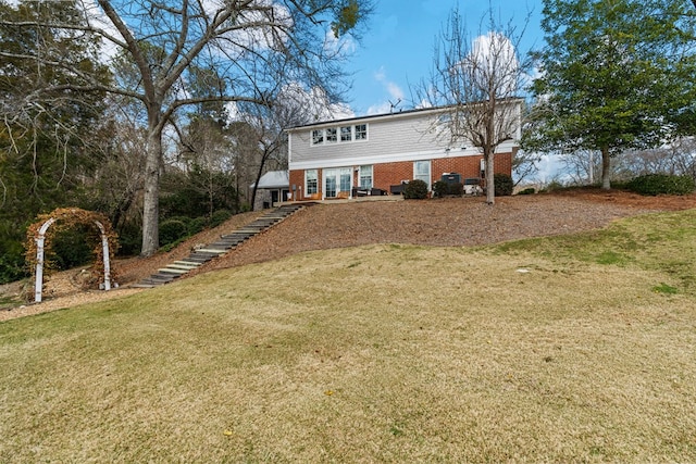 exterior space featuring stairs, brick siding, and a front lawn