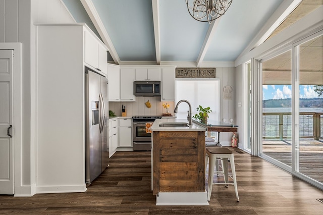 kitchen with a sink, appliances with stainless steel finishes, dark wood-style floors, and a center island with sink