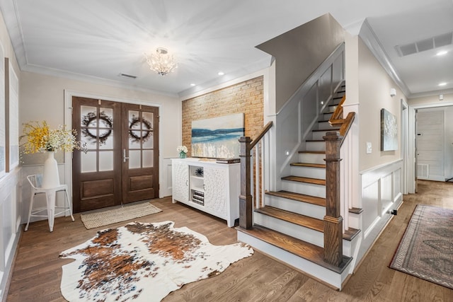 foyer entrance featuring stairs, wood finished floors, visible vents, and ornamental molding