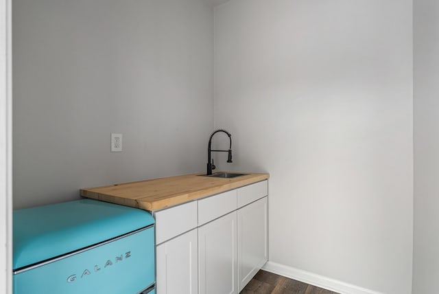 clothes washing area with a sink, baseboards, and dark wood-style floors