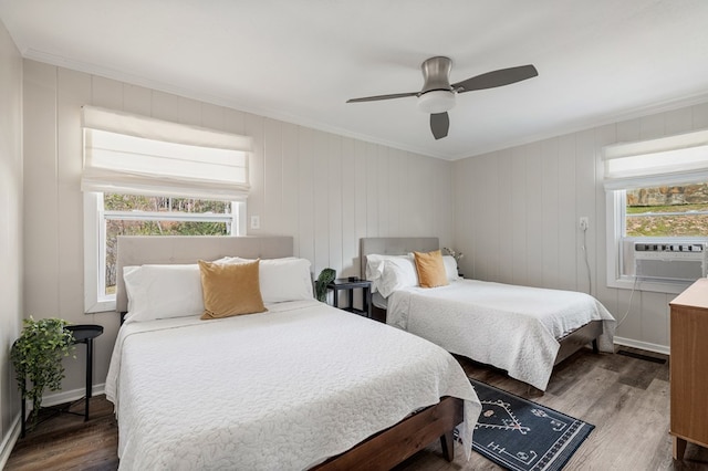 bedroom with cooling unit, wood finished floors, baseboards, and ornamental molding