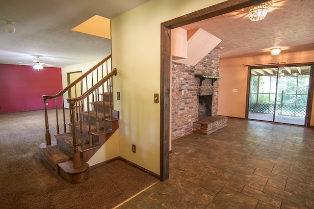 interior space with ceiling fan, a textured ceiling, and a brick fireplace