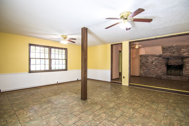 unfurnished living room featuring a brick fireplace and ceiling fan