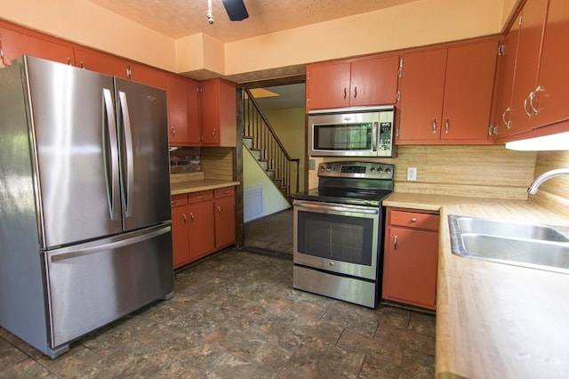 kitchen with backsplash, sink, stainless steel appliances, and a textured ceiling