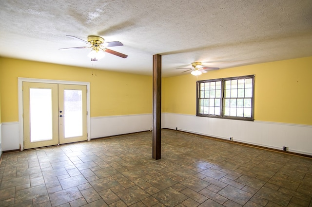 unfurnished room with french doors, a textured ceiling, and a wealth of natural light