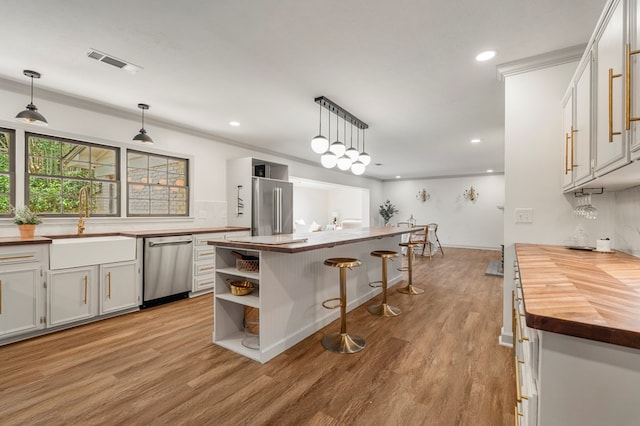 7172 Standing Boy Rd, Columbus, GA 31904 - kitchen with butcher block counters, appliances with stainless steel finishes, light wood finished floors, open shelves, and ornamental molding