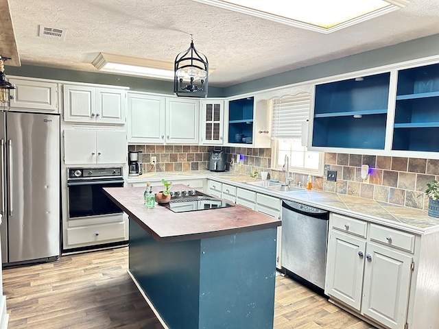 kitchen featuring a kitchen island, sink, black appliances, light hardwood / wood-style flooring, and white cabinetry