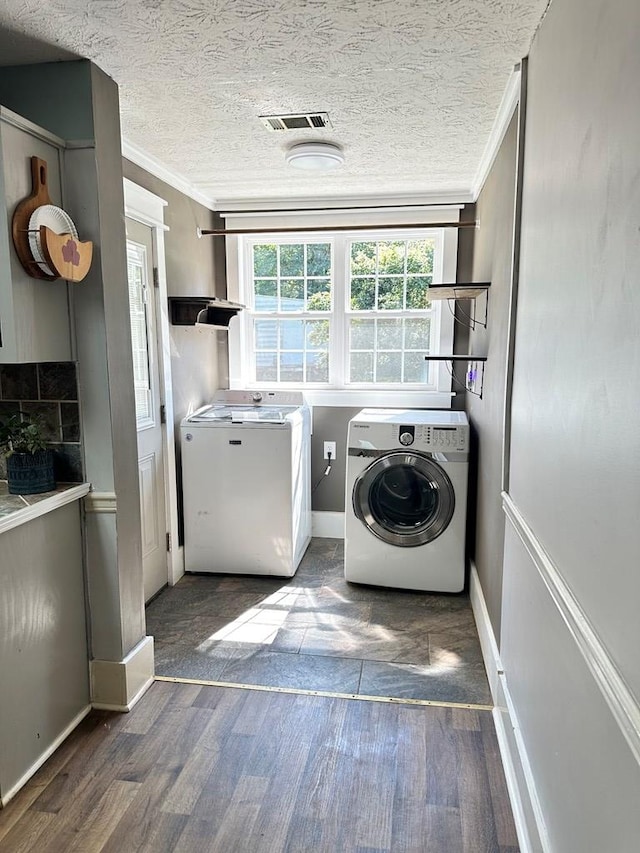 clothes washing area with a textured ceiling, dark hardwood / wood-style floors, crown molding, and washing machine and clothes dryer