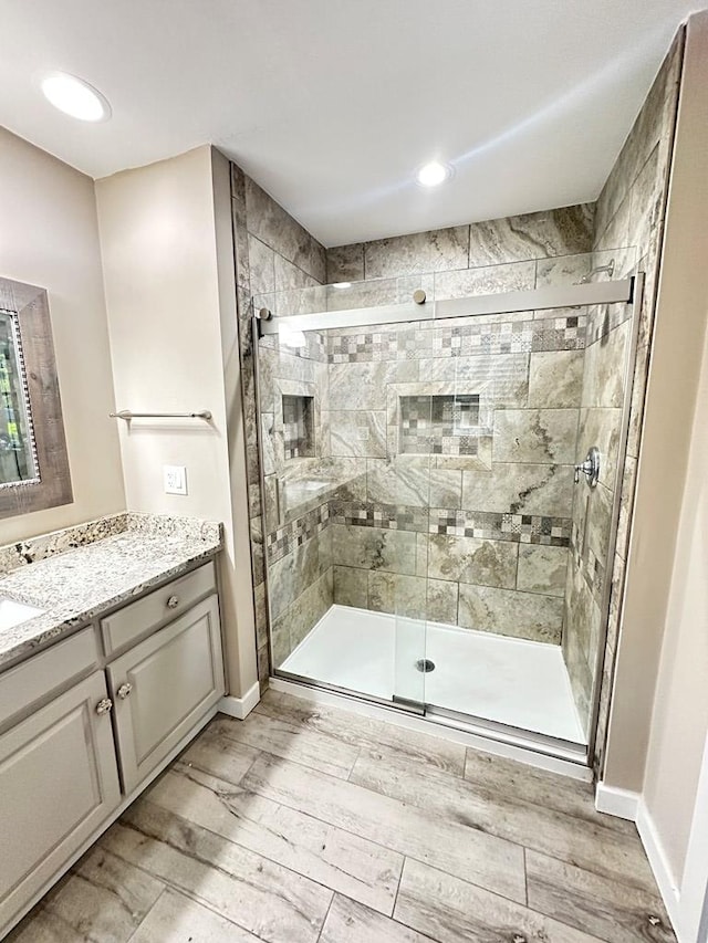 bathroom featuring a shower with door and vanity