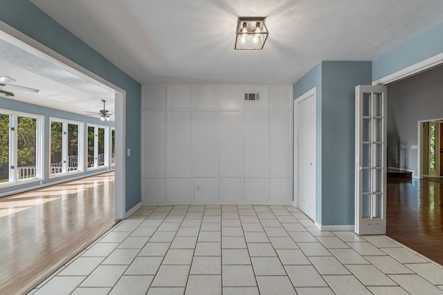 spare room with a decorative wall, plenty of natural light, a ceiling fan, and visible vents