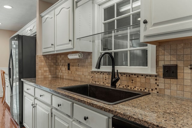 kitchen featuring white cabinets, a sink, freestanding refrigerator, recessed lighting, and decorative backsplash