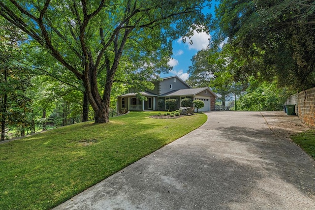 view of front of property featuring concrete driveway, a front lawn, and a garage