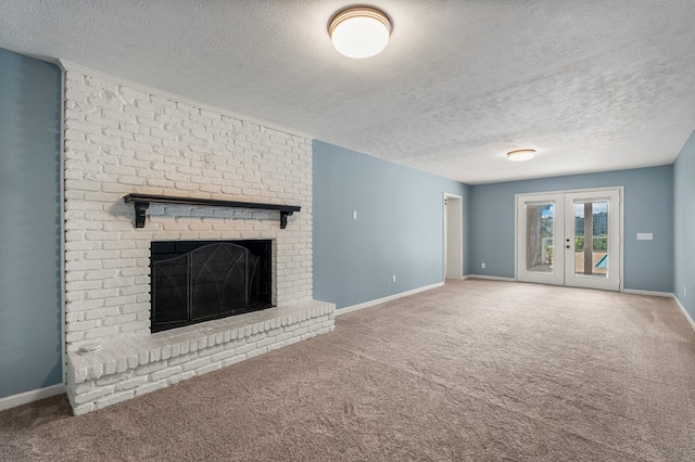 unfurnished living room featuring carpet flooring, a textured ceiling, baseboards, and a brick fireplace