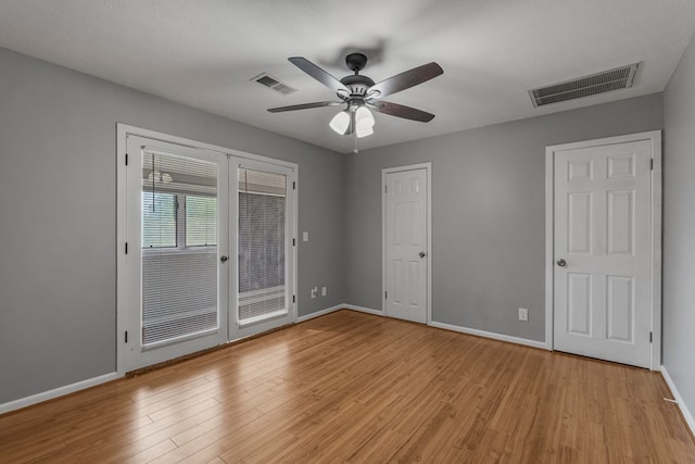 unfurnished bedroom with baseboards, french doors, light wood finished floors, and visible vents