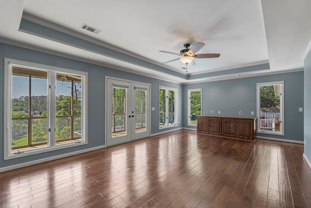 unfurnished living room featuring visible vents, ornamental molding, plenty of natural light, and a tray ceiling