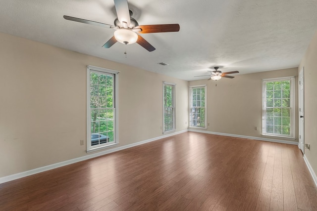 spare room featuring visible vents, hardwood / wood-style floors, baseboards, ceiling fan, and a textured ceiling
