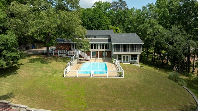 back of house with roof with shingles, a deck, an outdoor pool, french doors, and a lawn