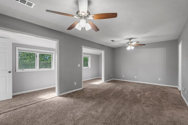 unfurnished room with a ceiling fan, baseboards, visible vents, and dark colored carpet